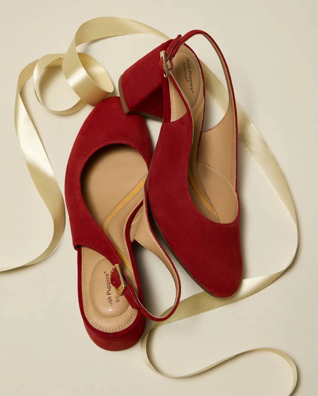 A pair of red wedge heels with a gold ribbon.