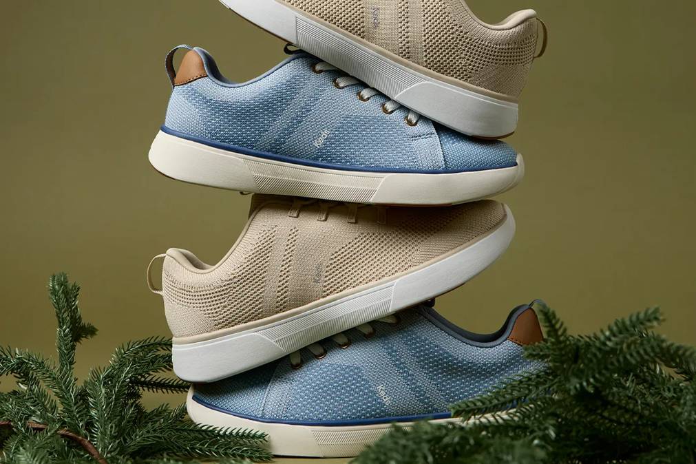 A stack of the BlissWalk Knit Lace-Ups sitting with pine branches.