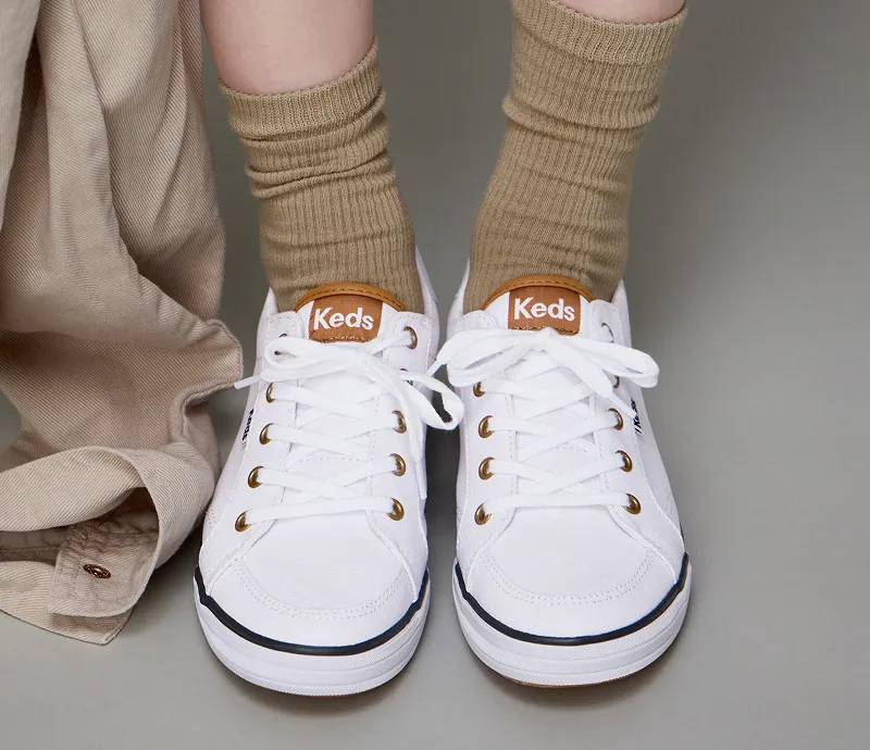 A pair of Center III Canvas Lace-Ups in white/navy show on foot paired with beige ribbed rocks.