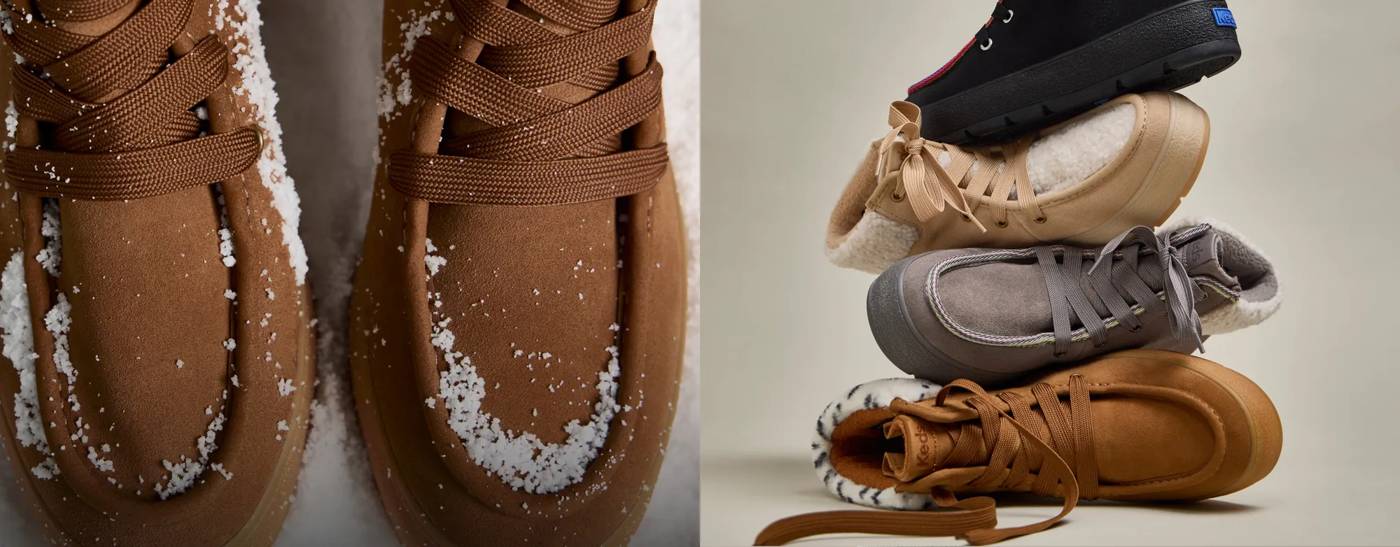 A close-up of a pair of Explore Suede Booties in dark brown sitting in snow next to a stack of four Explore Suede Booties in varying colorways. Text on the image says Cozy is in session. Shop boots.