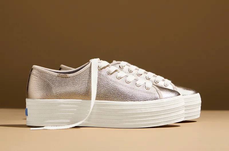 A side view of a pair of Triple Up Metallic Leather Lace-Ups in rose gold. Shop platforms.