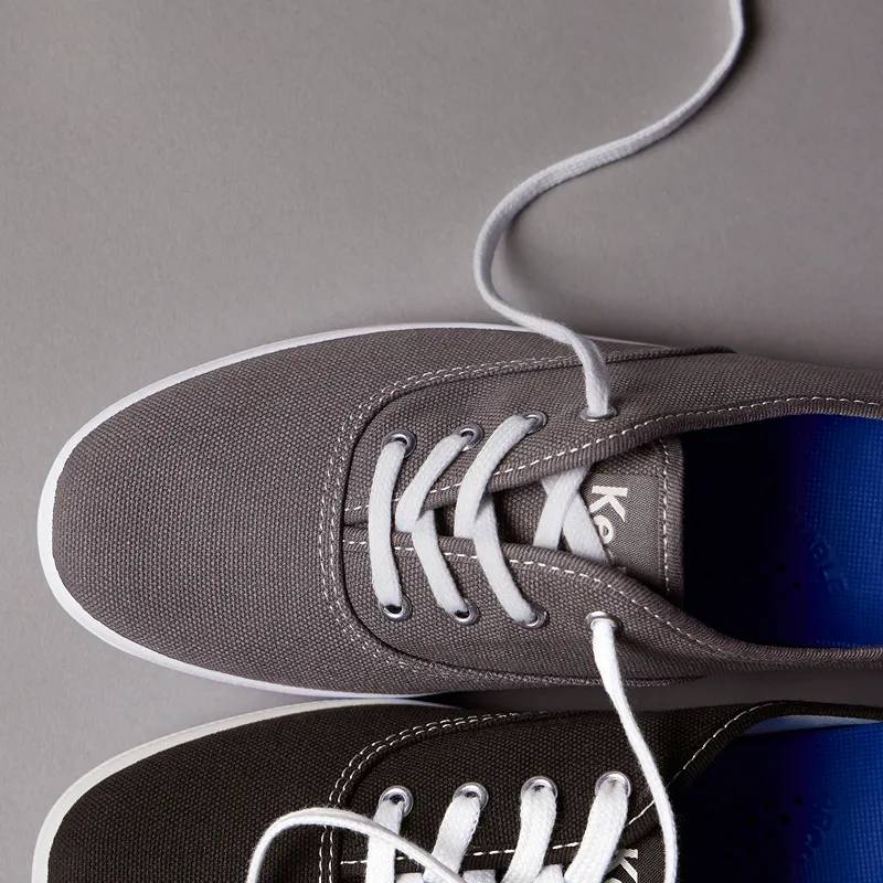A top-down view of a Keds Champion Canvas Lace-Up in grey and a Keds Champion Canvas Lace-Up in black. Icon Status. The sneaker that started it all. Shop Keds Champion.
