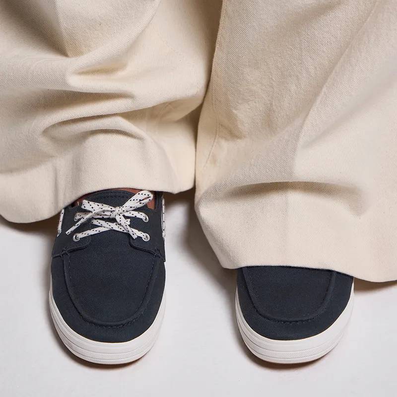 A top-down view of a pair of Center II Boat Twill Slip-On shown on foot paired with beige wide-leg trousers. Enhanced Comfort. All-day, everyday ease. Shop Comfort Collection