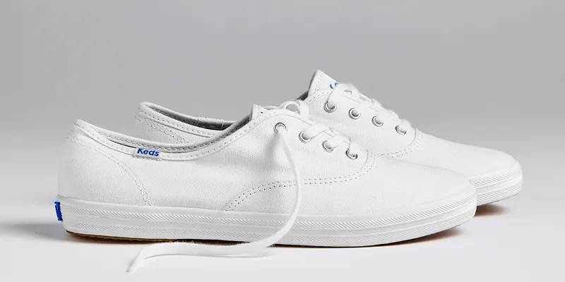 A side view of a pair of Keds Champion Canvas Lace-Ups in white. Shop Canvas Keds Champion Styles.
