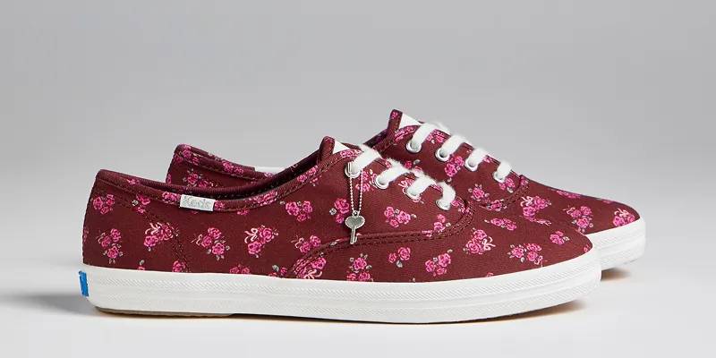 A side view of a pair of Keds Champion Canvas Printed Floral Lace-Ups in burgundy. Shop Exclusive Keds Champion Styles.