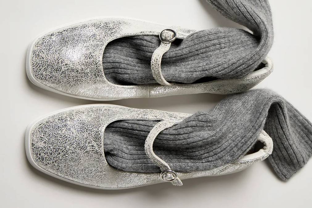 An overhead view of the Square Toe Mary Jane Distressed Metallic Leather in silver with long grey socks tucked into the shoes.