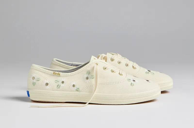 A side view of a pair of Keds Champion Canvas Floral Embroidered Lace-Ups in egret. Shop Lace-Ups.