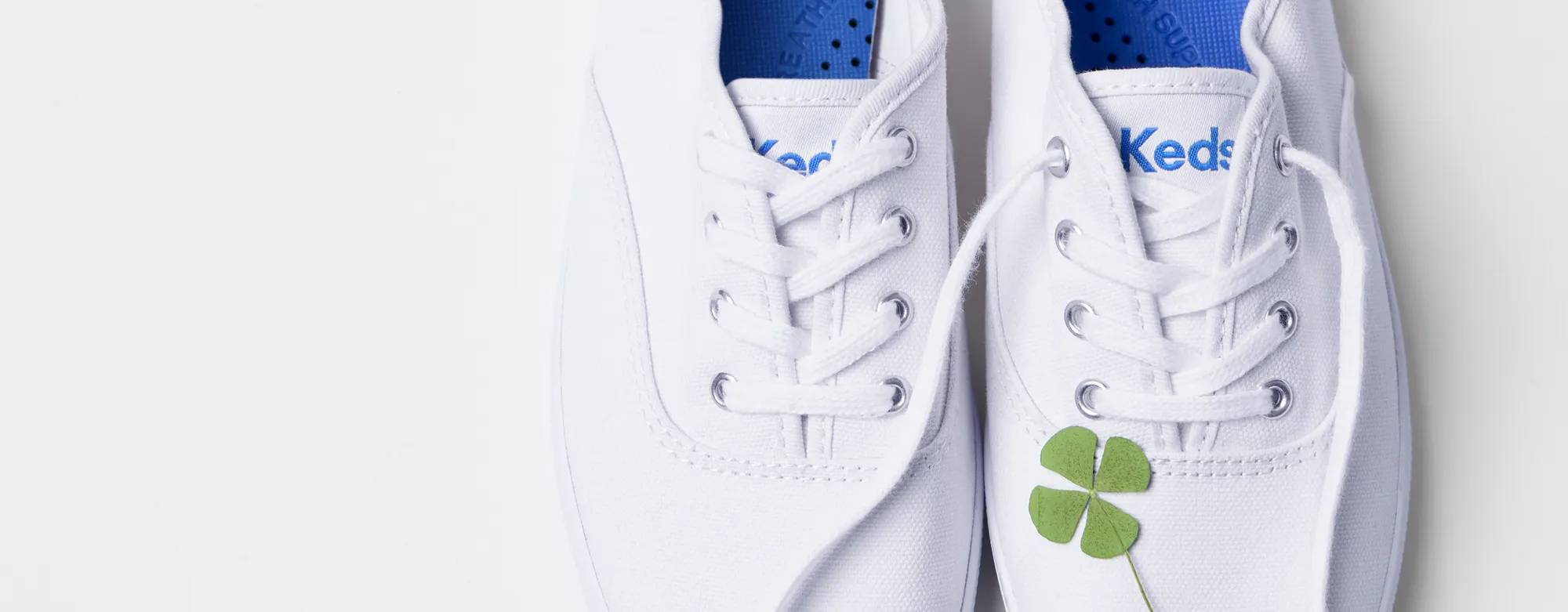 A green four-leaf clover sitting atop the Original Keds Champion Canvas Lace-Up in white. Text on the image says It’s Your Lucky Day! 30% Off Everything, Even Original Keds Champion. Use code: LUCKY. Exclusions apply.
