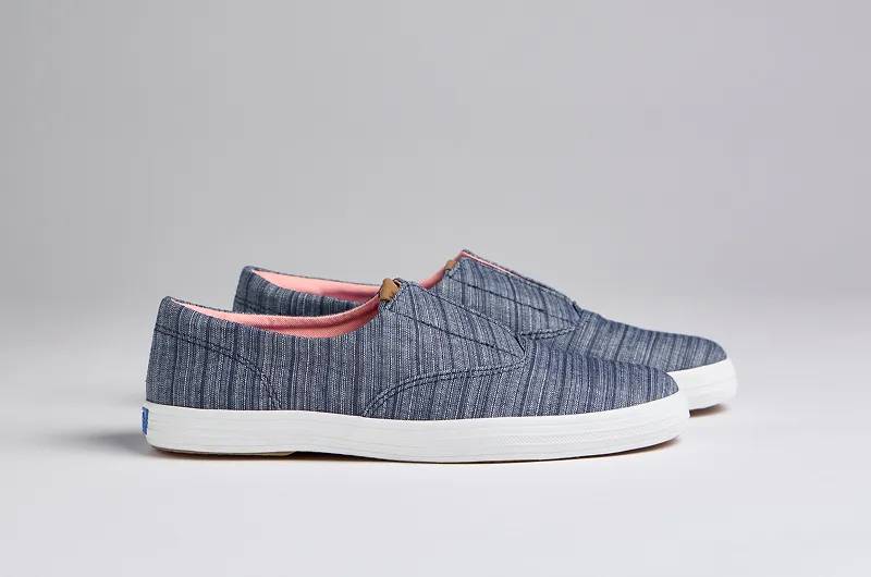 A side view of the Keds Champion Round Toe Stripe Chambray Slip-On in blue.