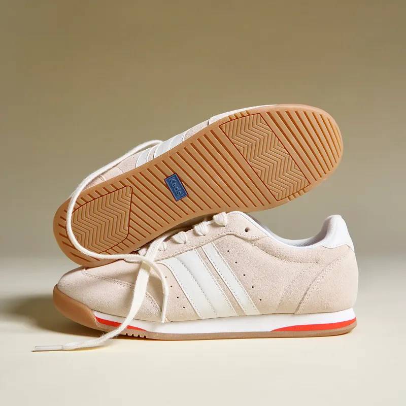 A dark to light beige background and a pair of the Revival Suede/Leather Lace-Ups in parchment/egret. One is positioned in a side view, the other on top, showing the rubber sole.