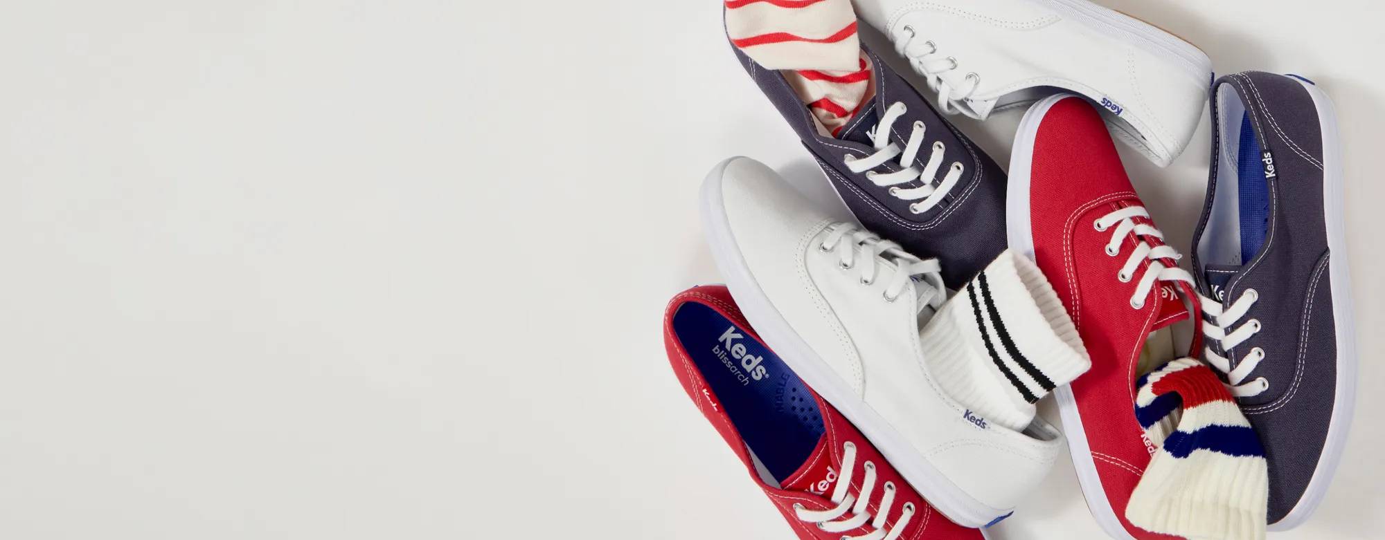 A group of Keds Champion lace-ups in white, red, and navy canvas shown from a top-down view, some styled with striped socks. The text says 30% Off Memorial Day Savings! Even Original Keds Champion. Use code: SUNSHINE. Exclusions apply. See details. Shop Now. Shop Keds Champion.