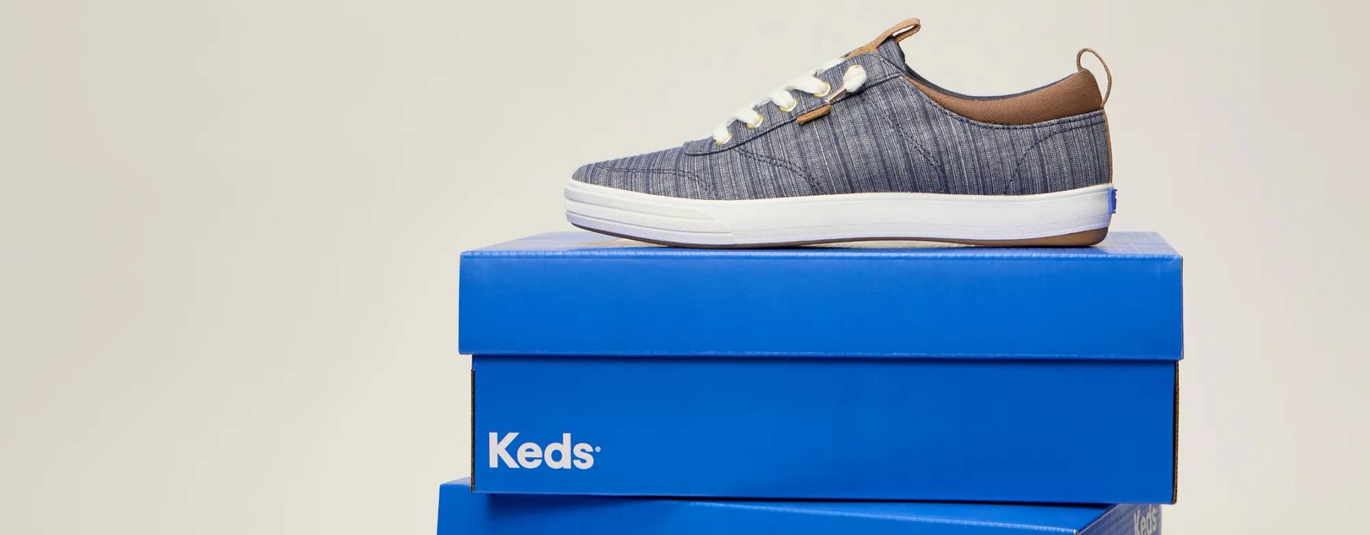 A stack of three bright blue Keds shoeboxes with the Center III Stripe Chambray Slip-On sitting on the top. Text above says Spring Finale Sale-on-Sale. Extra 35% Off Sale. New markdowns just added! Limited time only. Use code: EXTRA35. Shop Now.
