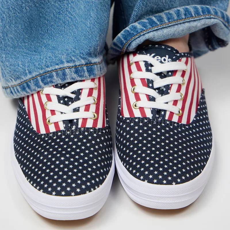 A pair of Keds Champion Twill Lace-Ups in an exclusive Fourth of July stars-and-stripes print shown on foot paired with medium-wash jeans.
