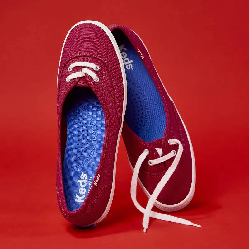 A pair of Mini Canvas Slip-Ons in red positioned upright to showcase the molded arch support of the sneaker’s footbed.