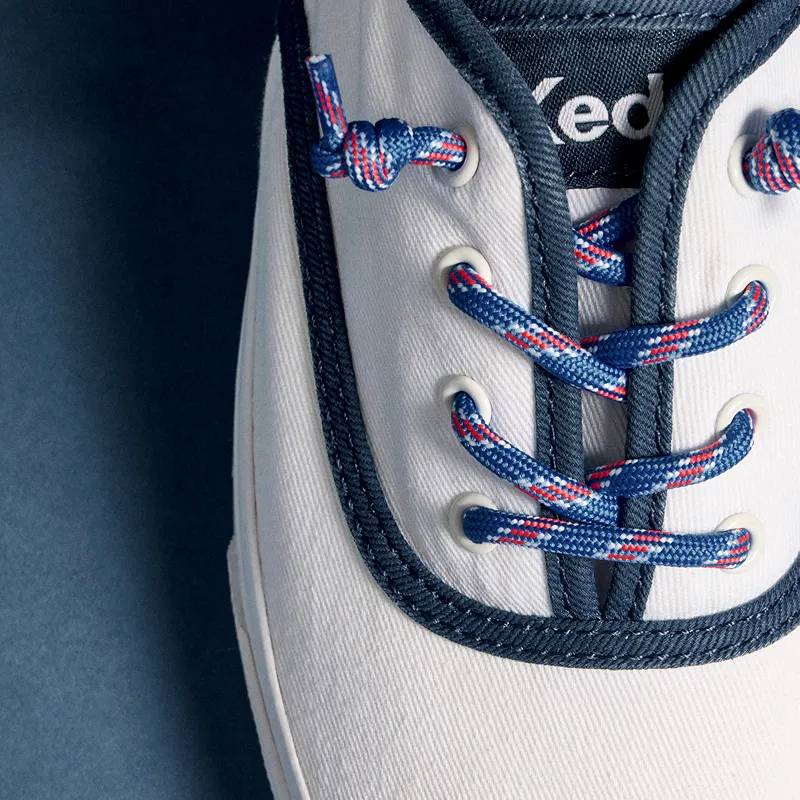 A top-down closeup of the Rillax Champ Washed Twill Pop Binding Slip-On in snow white/navy showcasing the colorful fixed shoelaces.