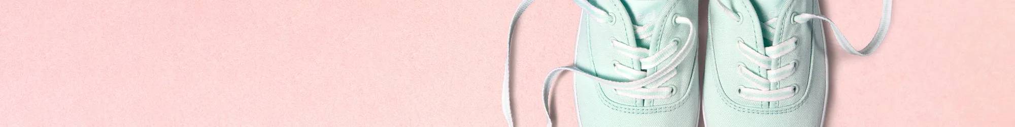 A top-down closeup of the Keds Champion Canvas Lace-Up in bay blue sitting on a light pink background with the laces untied.