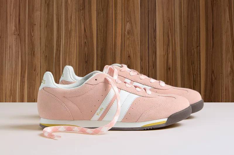 A side view of a pair of Revival Suede Lace-Ups in peach against a wood-paneled background. Shop Lace-Ups.