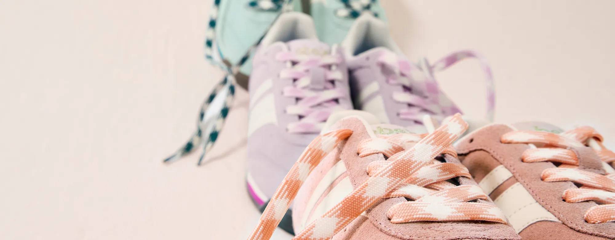 A lineup of three pairs of new Revival Suede Lace-Ups. The pair in front is in peach, the pair in the middle is in lavender, and the pair in the back is in mint. All three pairs feature matching plaid shoelaces. Text on the image says Revival Remix. Shop new colors.