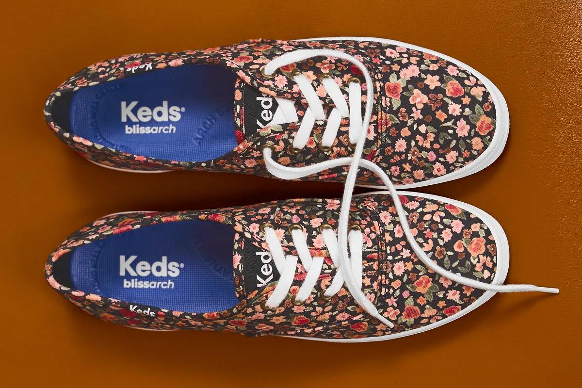 A top-down view of a pair of Keds Champion Canvas Lace-Ups in ditsy rose. Text below says In With the New. Shop new arrivals.