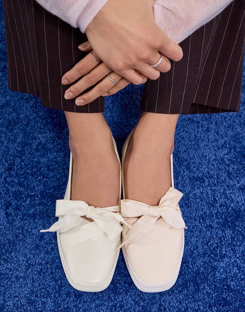 An overhead view of the Square Toe Leather Ballet in white pearlized on one foot and fall blush on the other positioned on a blue carpet.