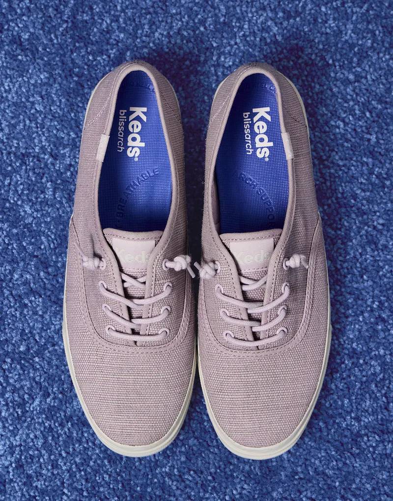 A top-down view of a pair of Rillax Champ Chalky Canvas Slip-Ons in lavender sitting on a vivid blue carpet.