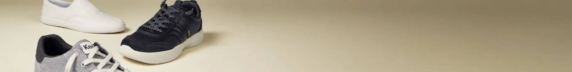 A beige background features a the Center III Two Tone Textile Lace-Up in grey/white in the foreground pointing toward the right, the BlissWalk Ubal Lace-Up in black in the middle pointing toward the left, and Keds Champion Square Toe Soft Leather Slip-On in white pointing toward the right. The text says Fall Favorites Sneaker Sale $35 Sneakers. Select styles only. See details. Use code: SNEAKS35 Shop Now