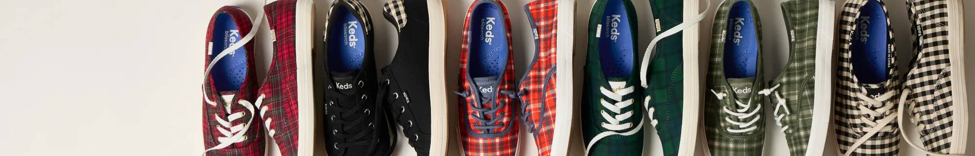 A closeup view of the Keds Champion School Plaid Canvas Lace-Up in green/navy showcasing the sneakers’ golden eyelets. Text above the sneaker says Fall’s It Print: Plaid.