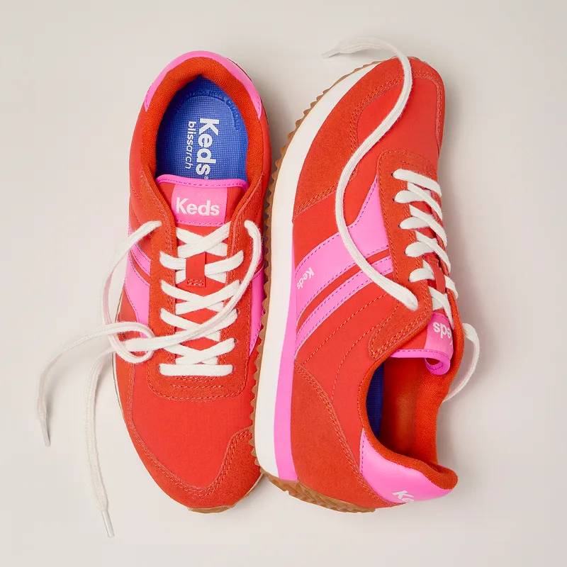 A grey background with a pair of the Rena Nylon/Suede Lace-Ups in red/fuchsia facing opposite directions.