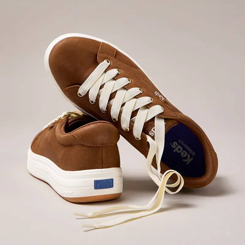 A grey background with a pair of the Park Leather Lace-Ups in dark cognac, one propped up on the other.