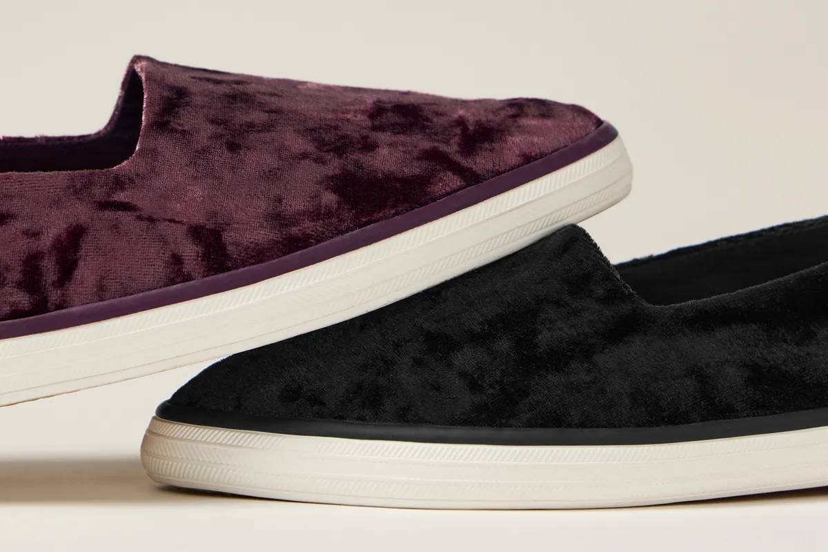 A close-up of the Point Slingback Crushed Velvet in fig overlapping the same style in black.