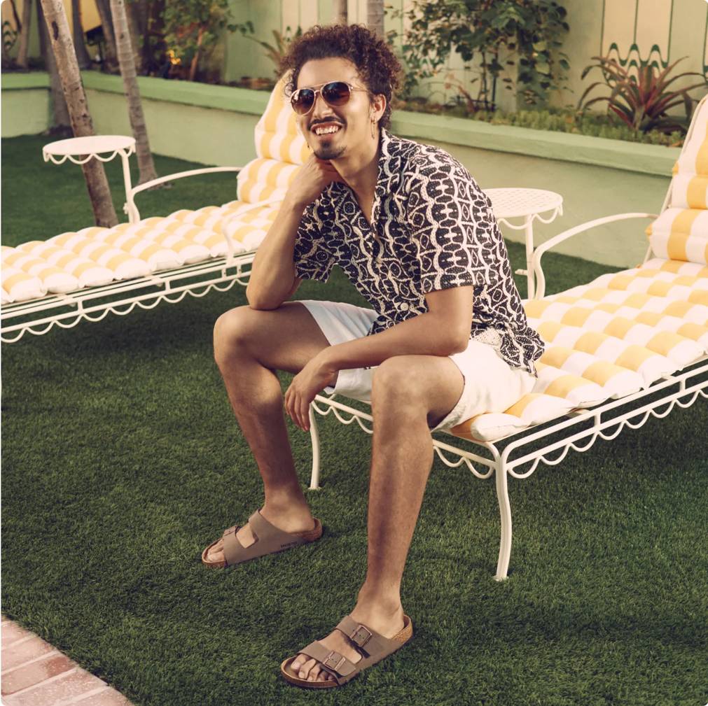 Man sitting on outdoor lounge chair wearing brown Birkenstock sandals