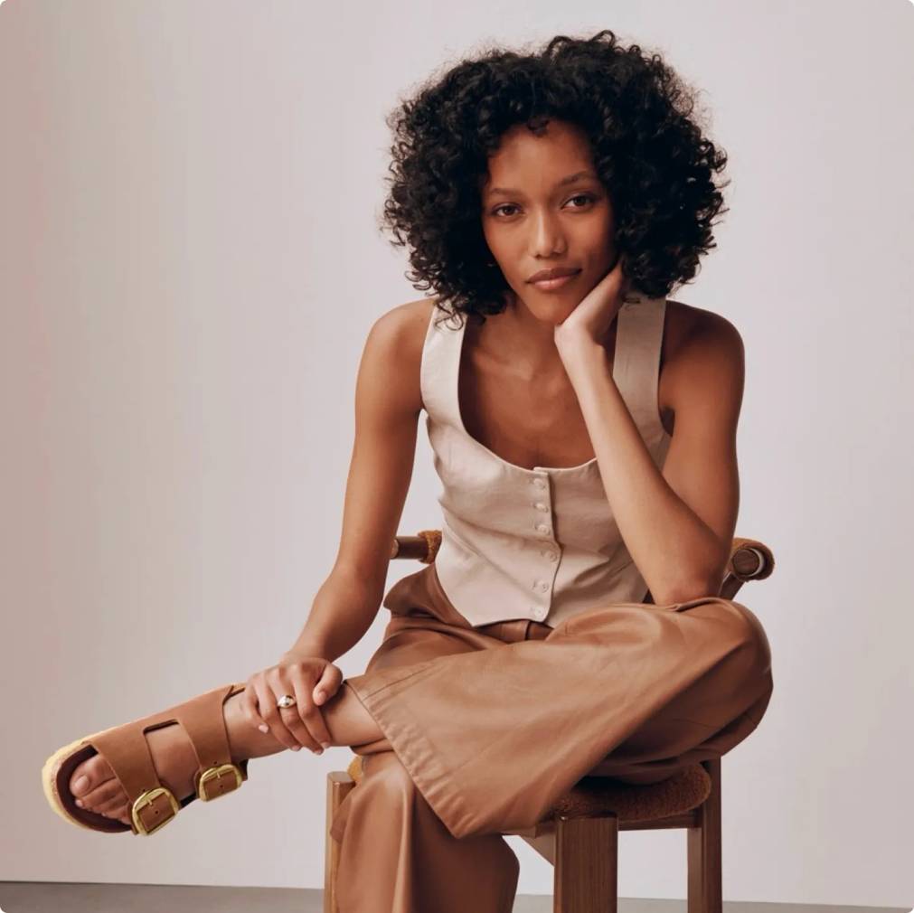 Woman sitting in a chair while wearing brown Birkenstock sandals