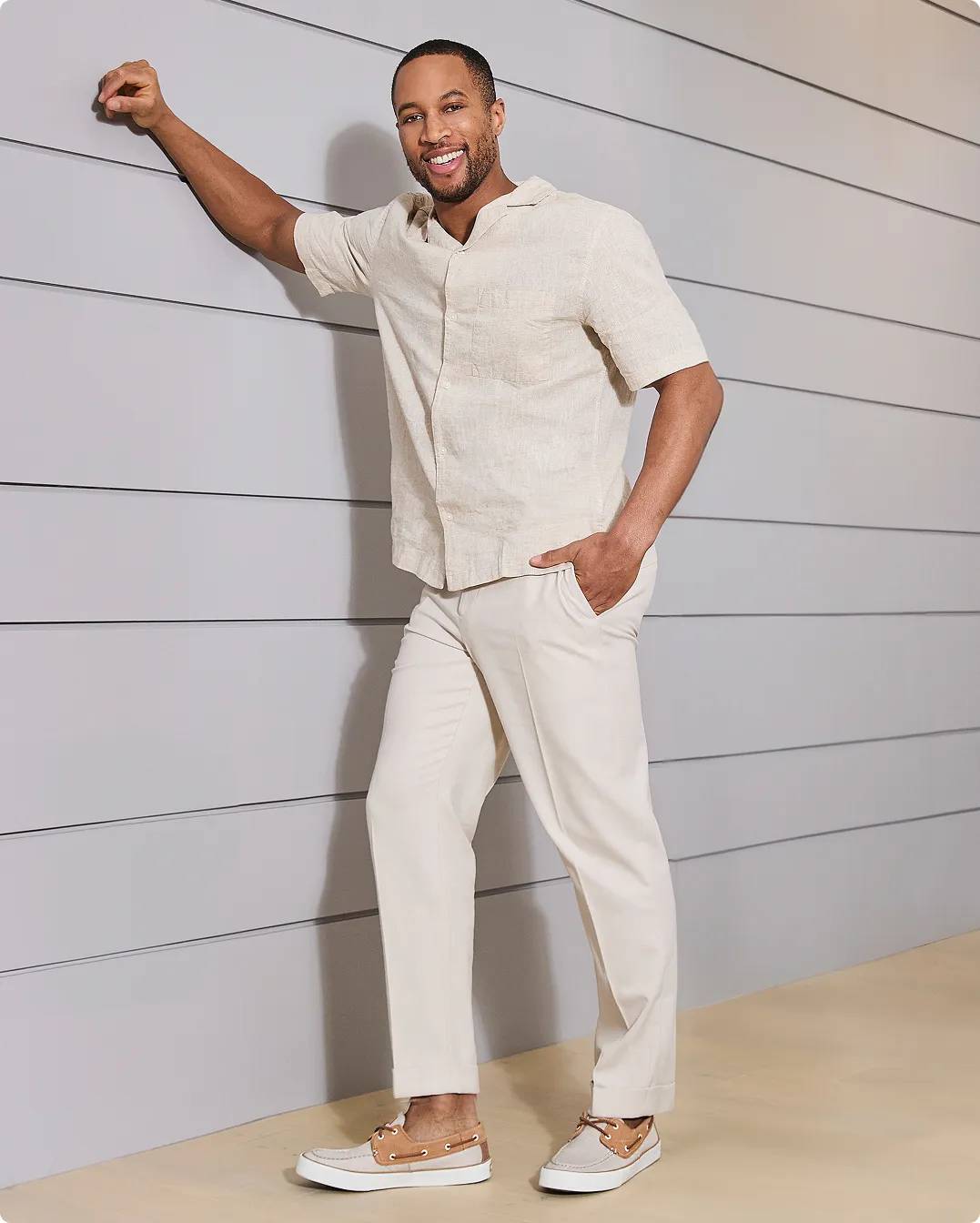 Man leaning against the wall wearing tan and beige boat shoes