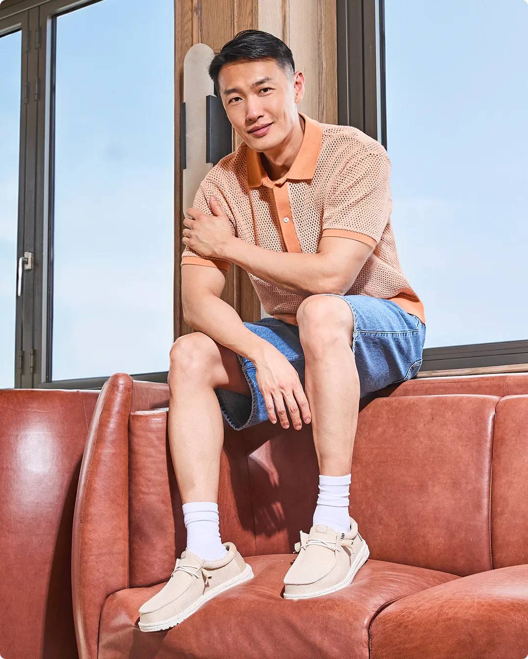 Man sitting on the couch wearing beige Hey Dude casual shoes