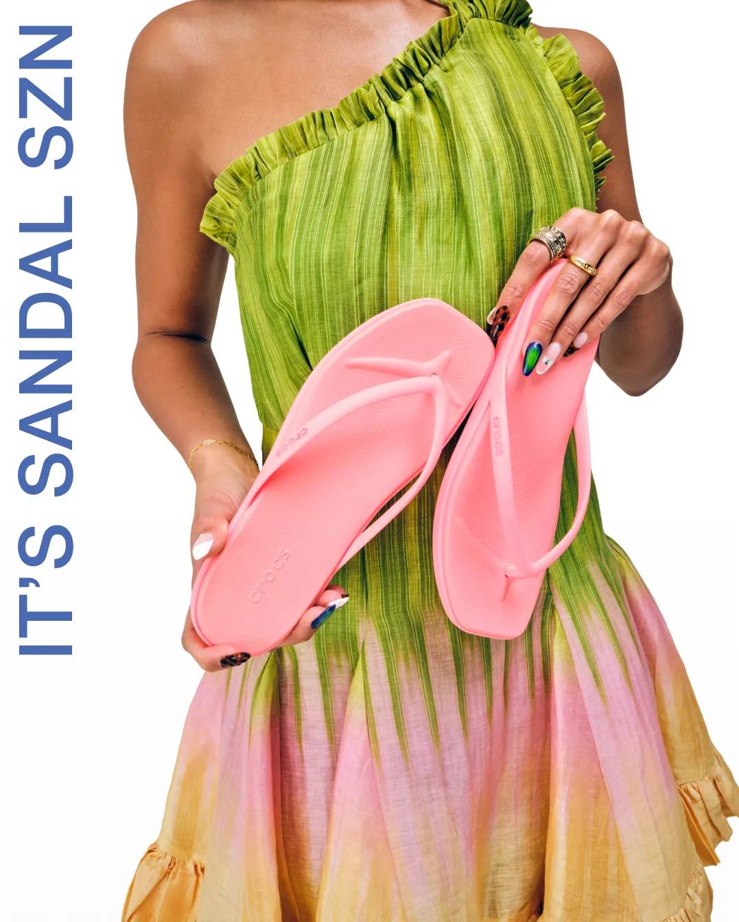 Woman in green dress holding up pink flip flops