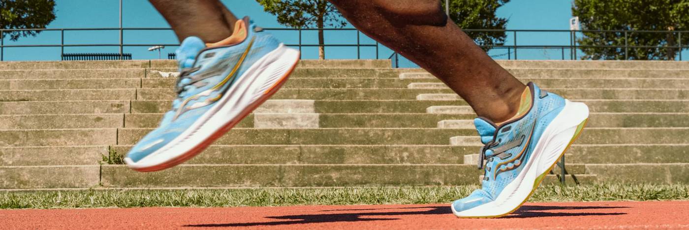 A person runs on an outdoor track wearing brightly colored running shoes