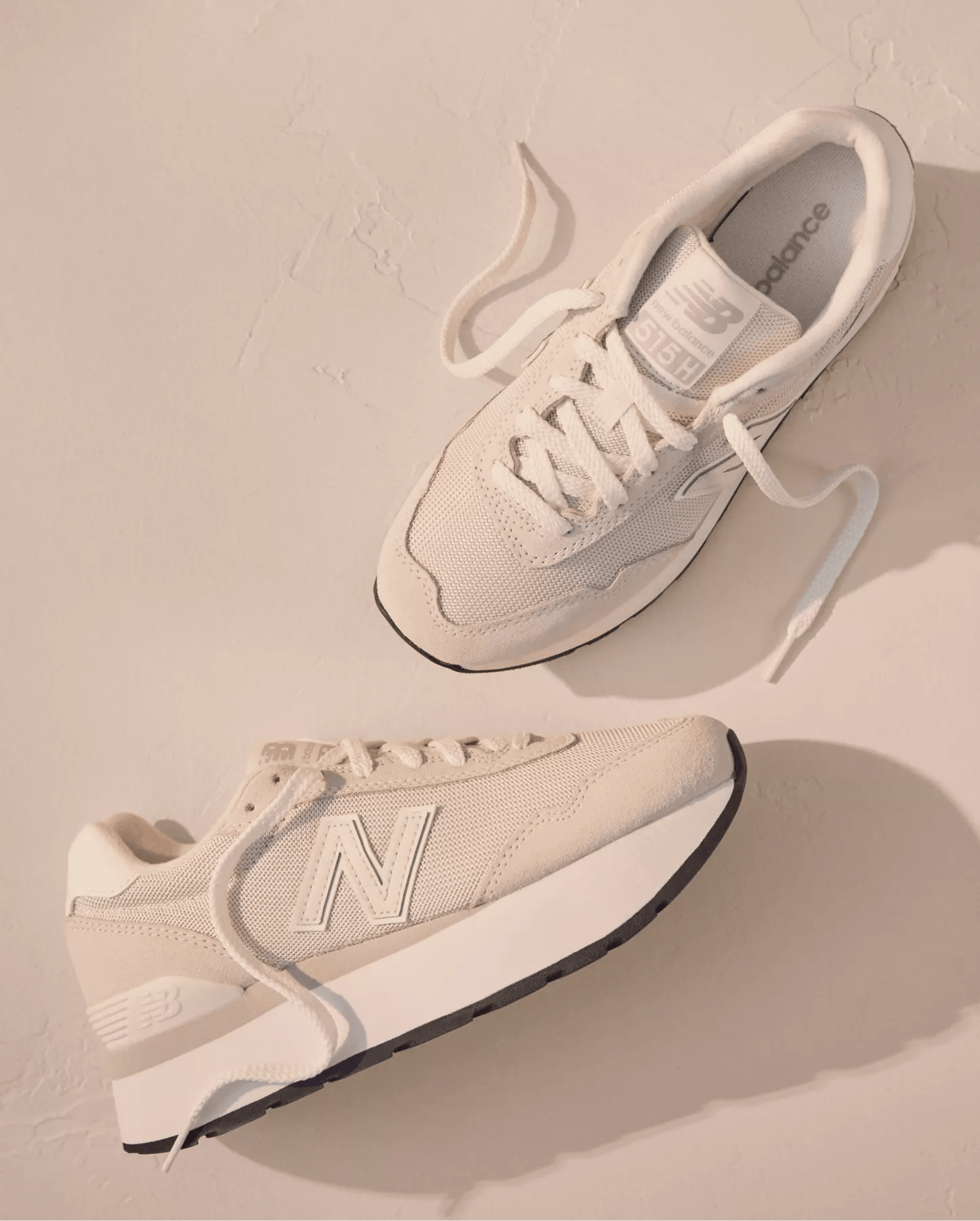 Two white sneakers on a beige background