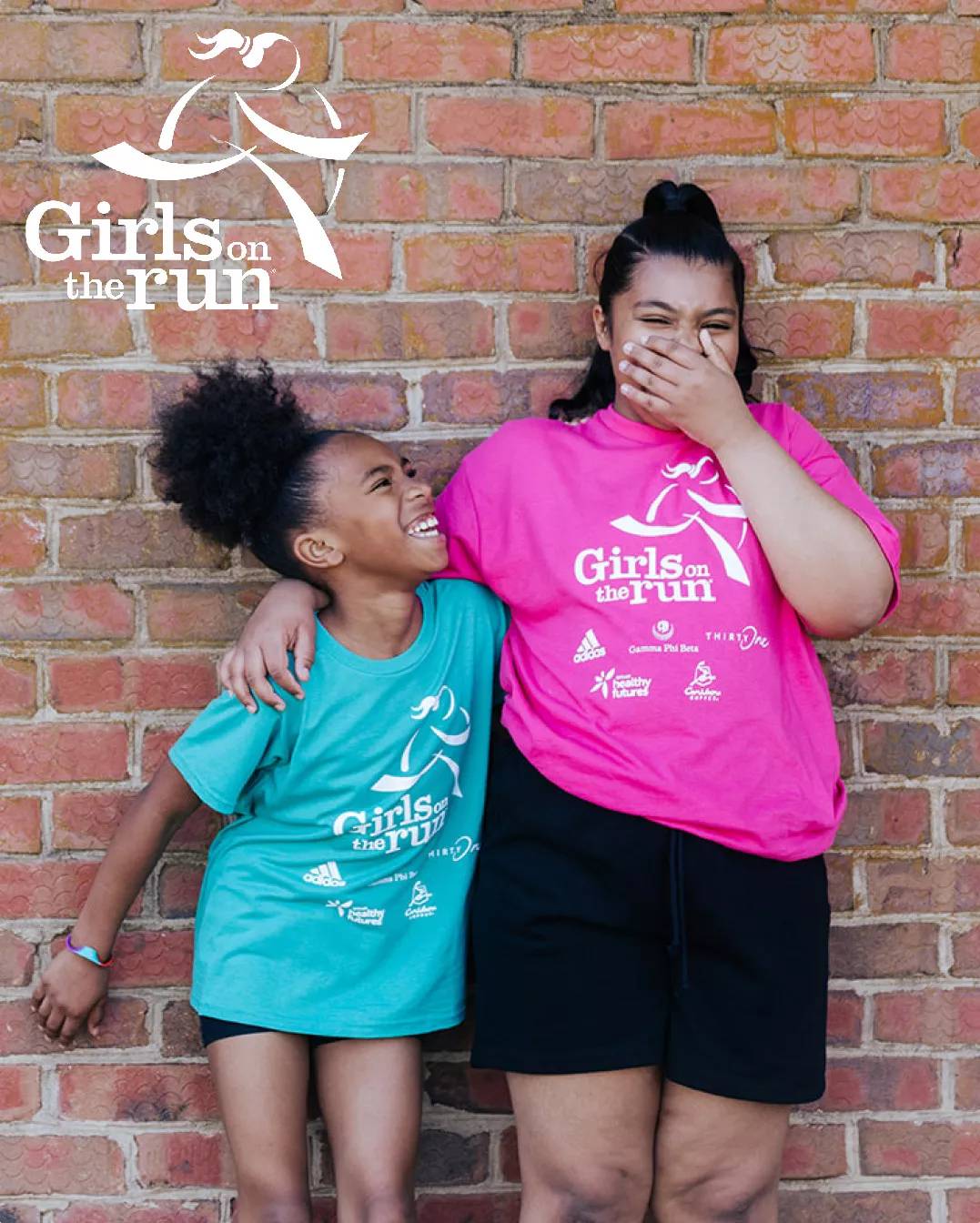 Featuring the Girls on the Run logo and two young girls wearing Girls on the Run t-shirts, smiling and giggling.
