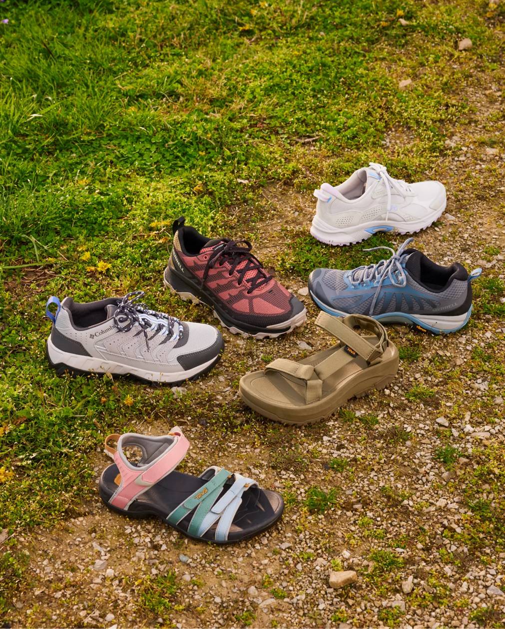 Several women's walking shoes and sandals on a grass background