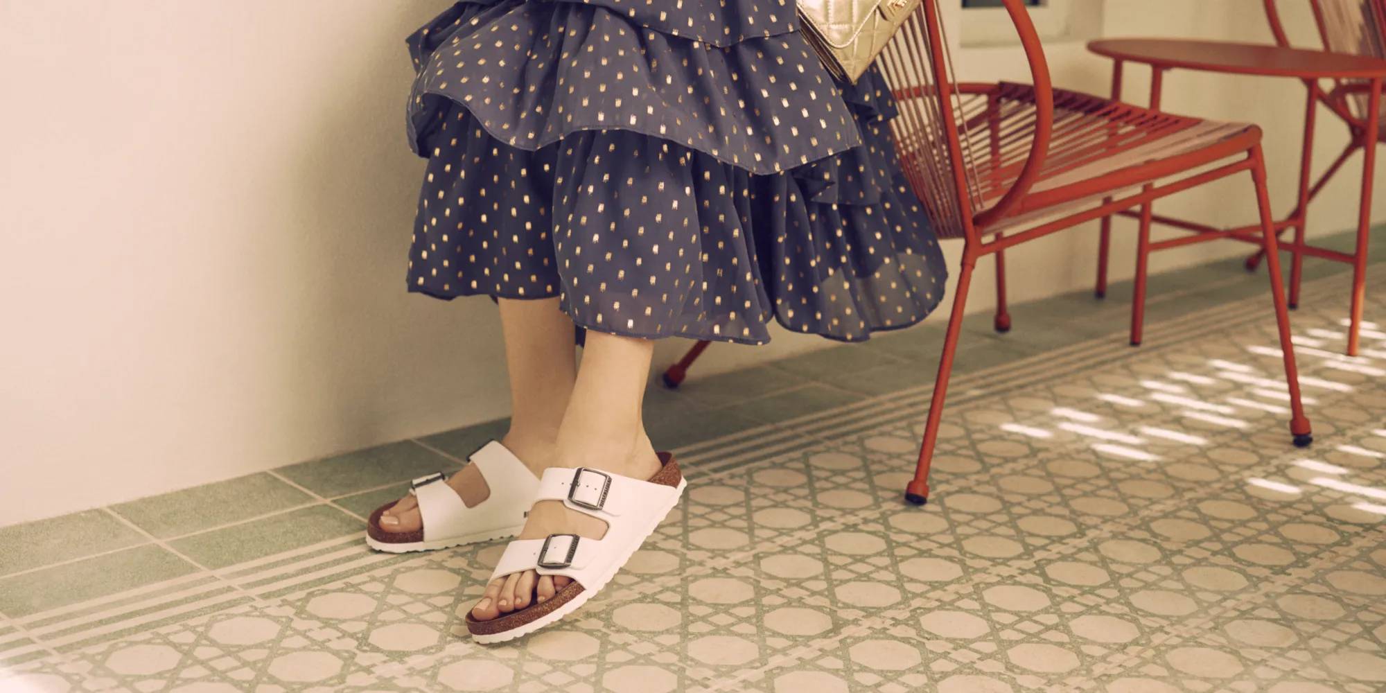 Women in a long dress wearing white Birkenstock sandals.