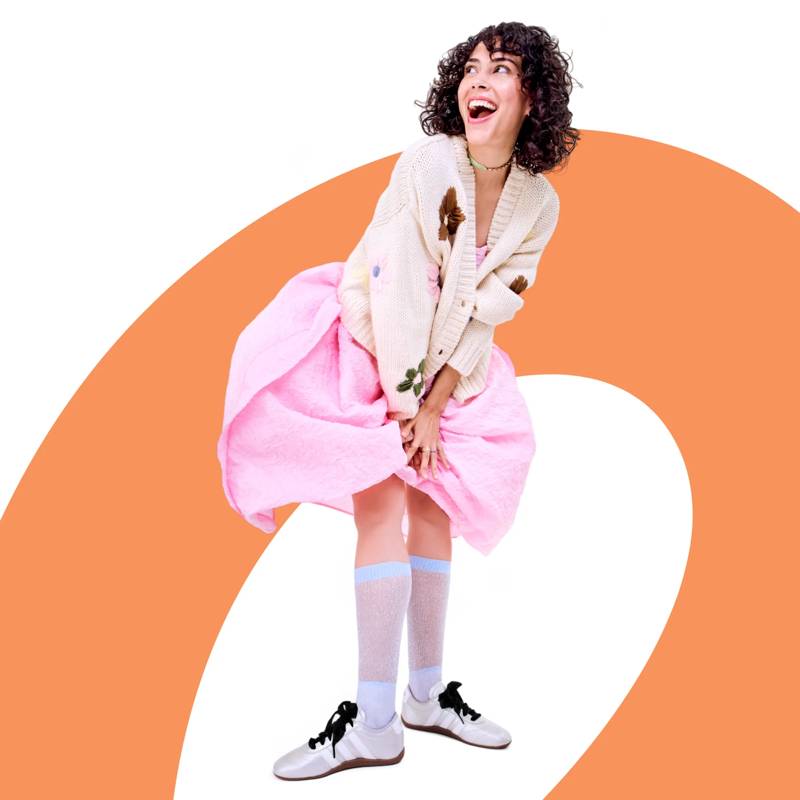 Model wearing low profile sneakers paired with a dress and cardigan.