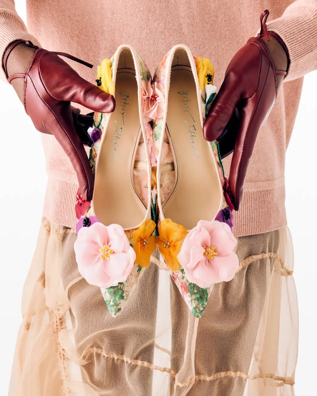 Featuring a model holding a pair of floral betsey johnson flats.