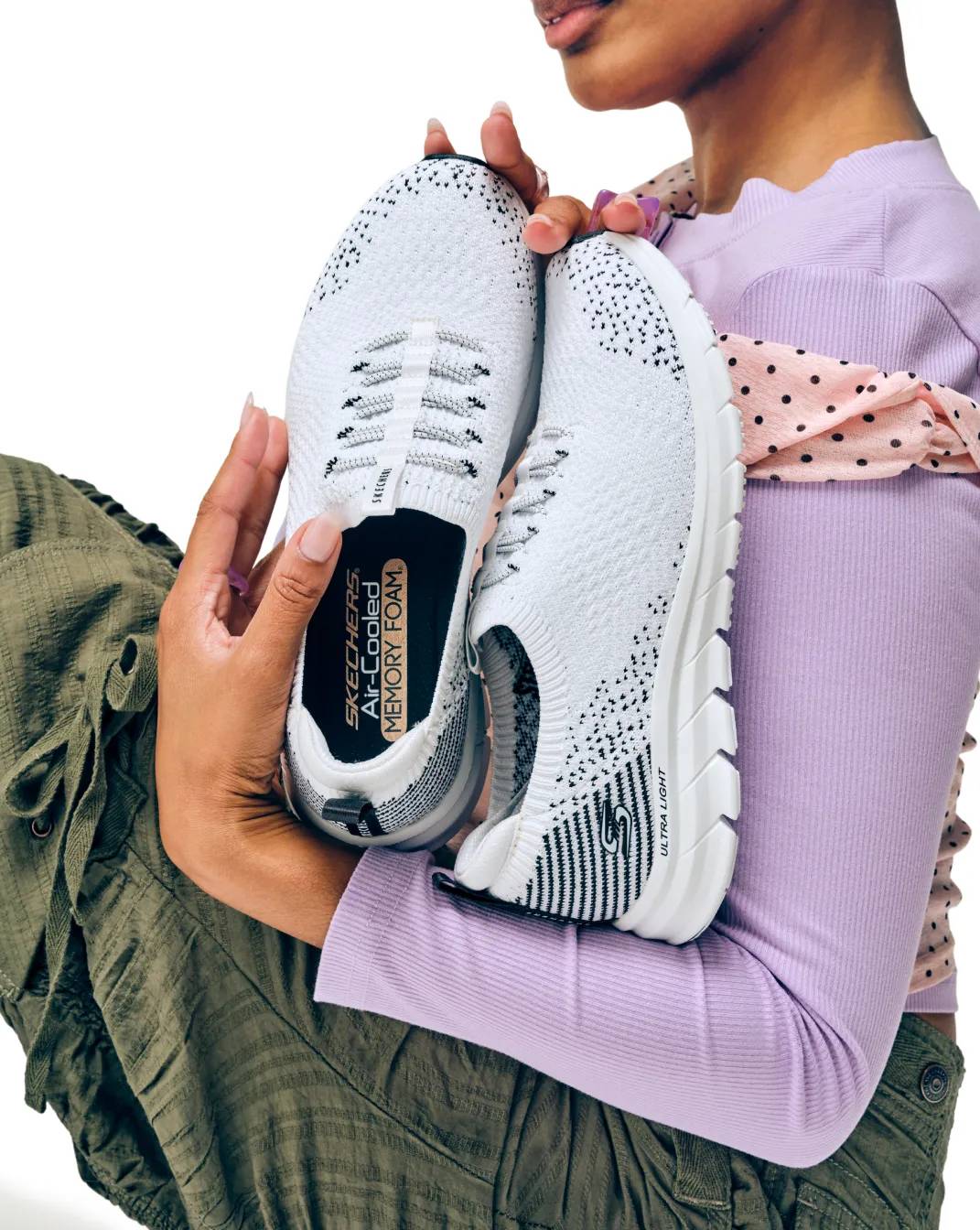Featuring a model holding Skechers Sneakers.