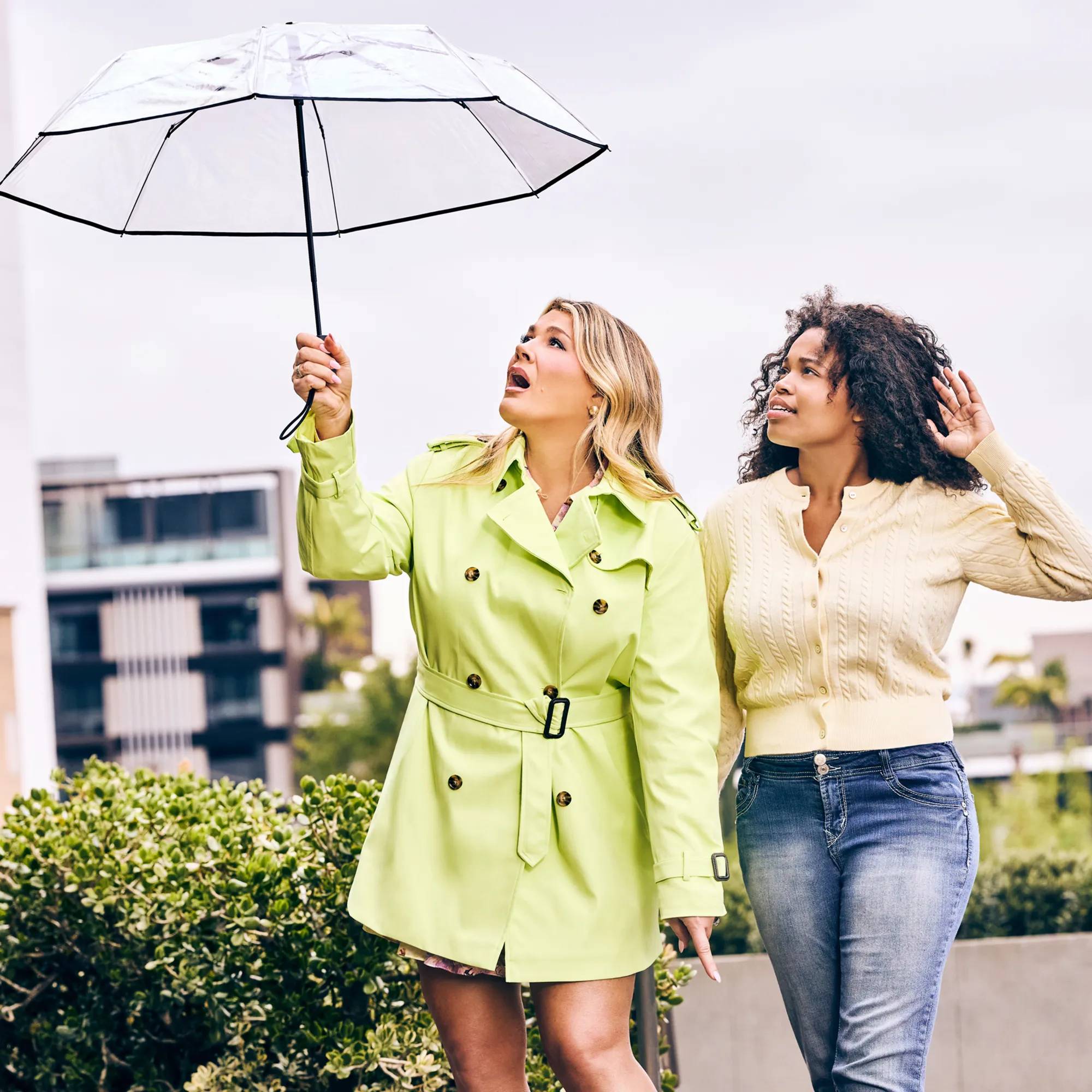 Featuring Heather McMahan and a friend outside with an umbrella looking at the sky in disbelief.
