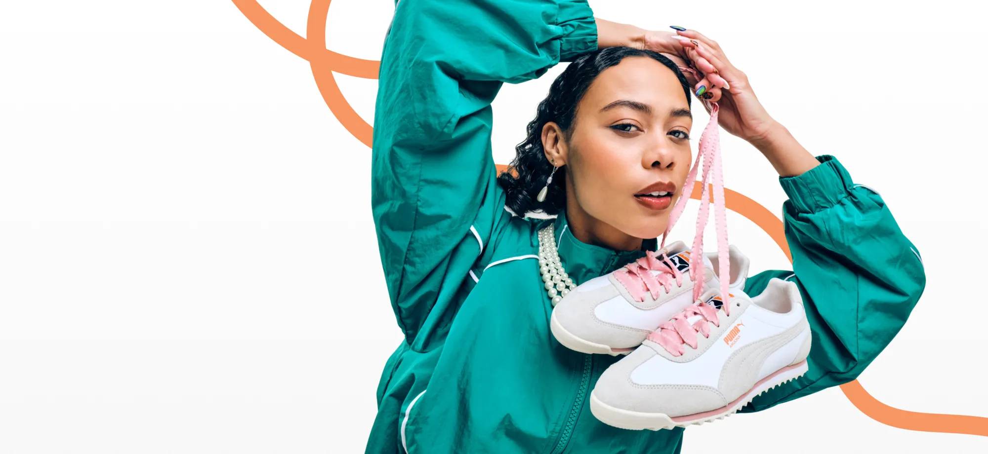 Featuring a woman wearing a retro jacket and holding a pair of Puma sneakers.