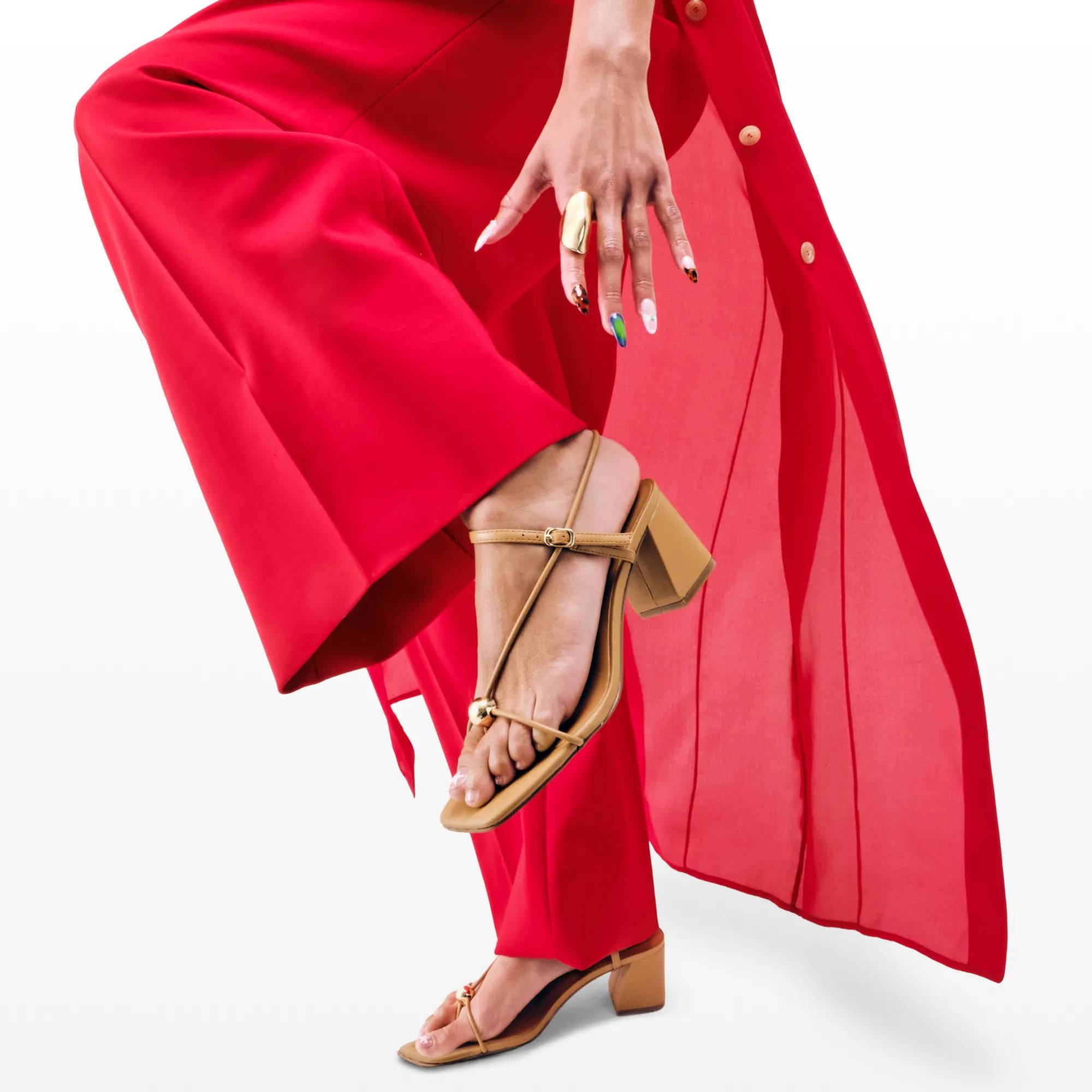 Featuring a woman wearing red pants and nude dress sandals.