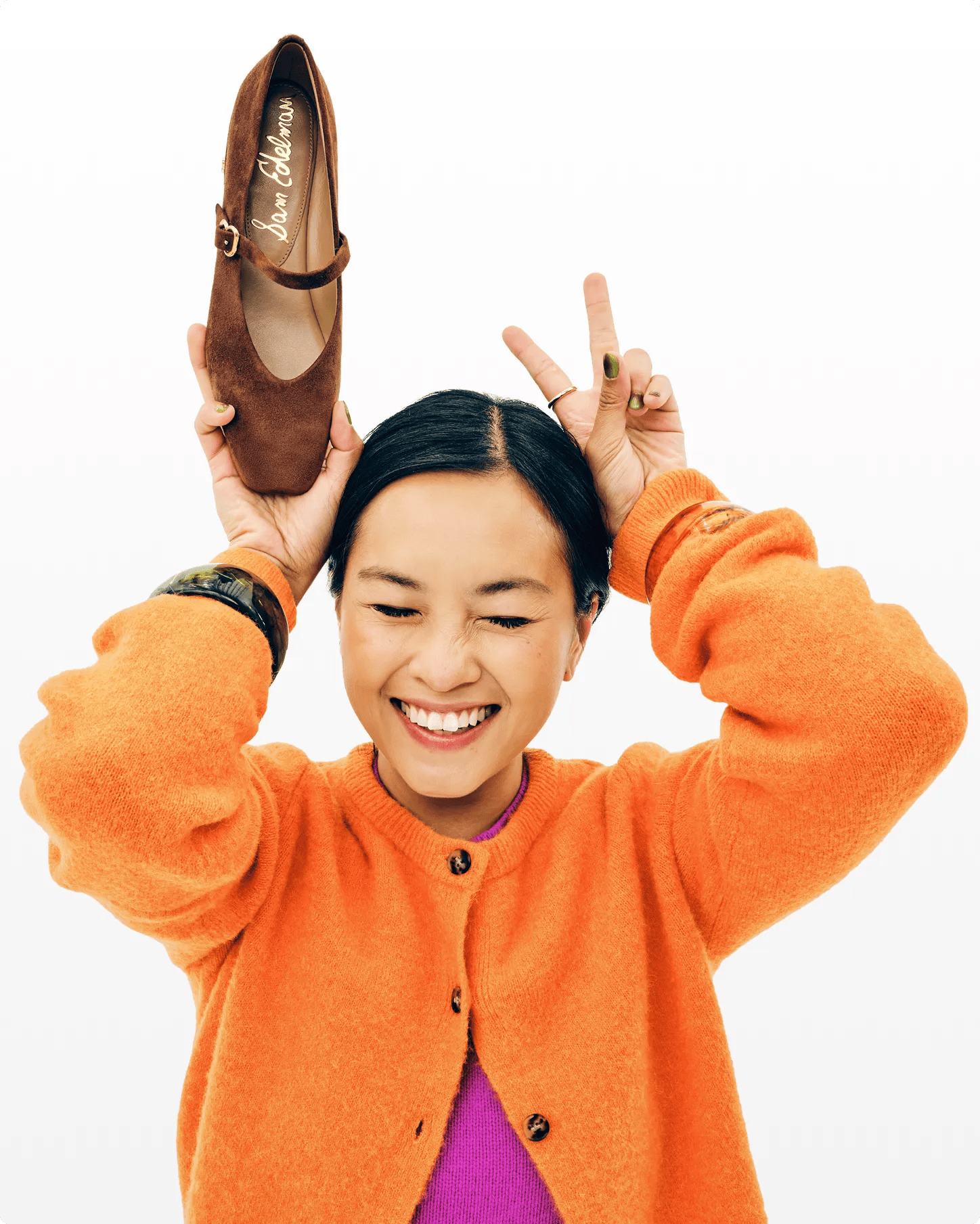 Featuring a woman holding up a suede mary jane.