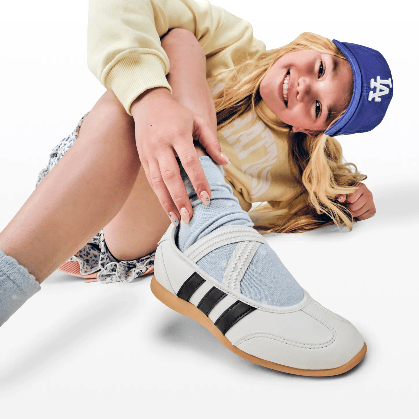 Featuring a model in kids Adidas sneakers.