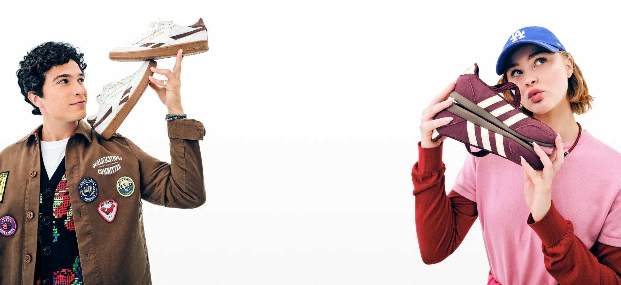Featuring a male and a female model both holding up a pair of fashion sneakers.