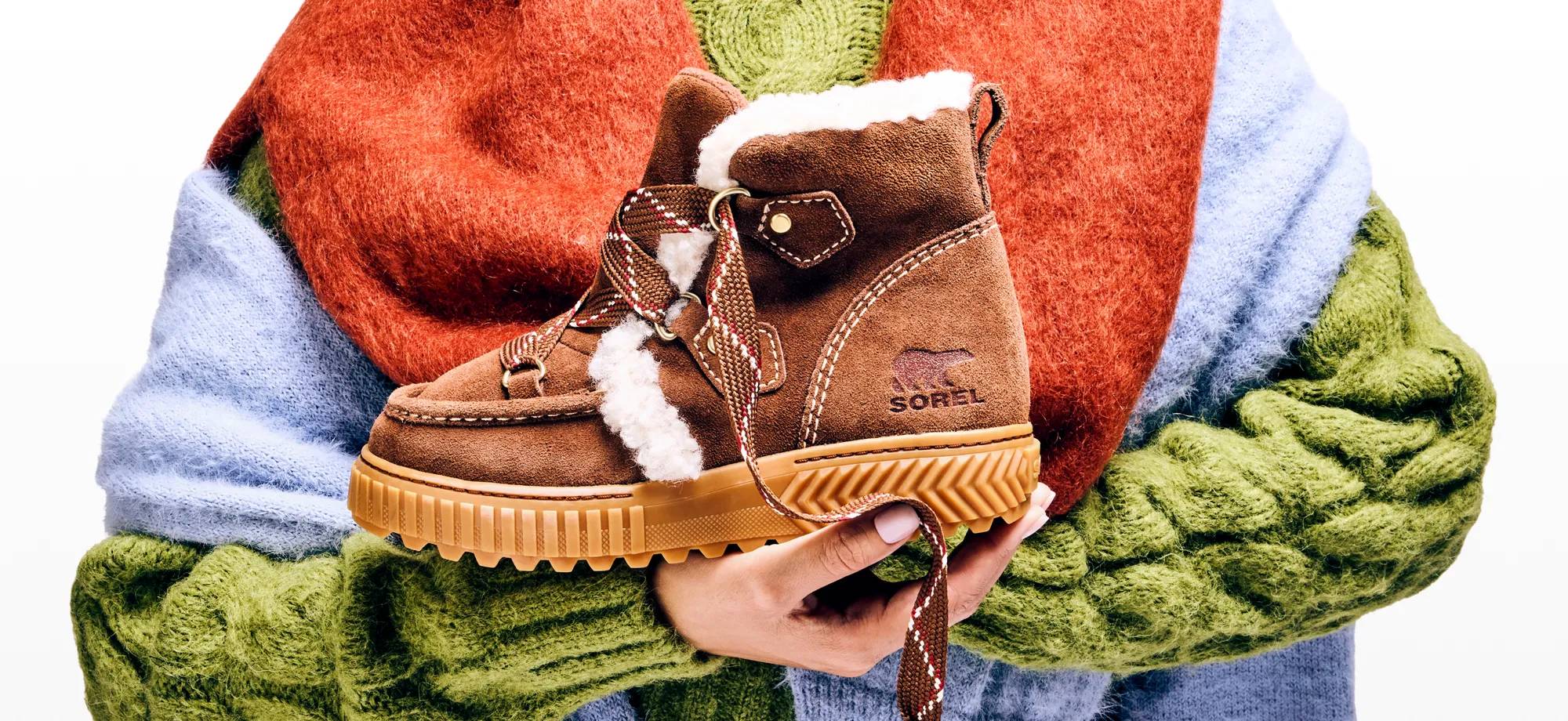 Woman holding Sorel shearling lined cold weather boots.
